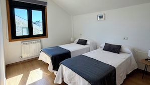 Une chambre avec deux lits, une fenêtre donnant sur un beau paysage, un radiateur et une petite table.