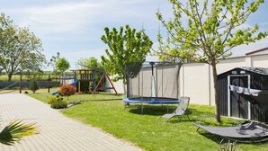 Ein Spielplatz mit Rutsche, Trampolin und Schaukeln.