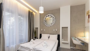 Une chambre d’hôtel moderne avec un lit bien fait, un miroir rond accroché au mur et un bureau avec une chaise.
