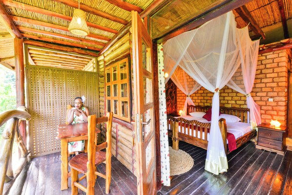 A wooden room with a bed, a table, and a chair. - Serenada Eco Resort  (Mukono)