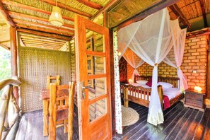 A wooden room with a bed, a chair, a nightstand, and a woven mat. - Serenada Eco Resort  (Mukono)