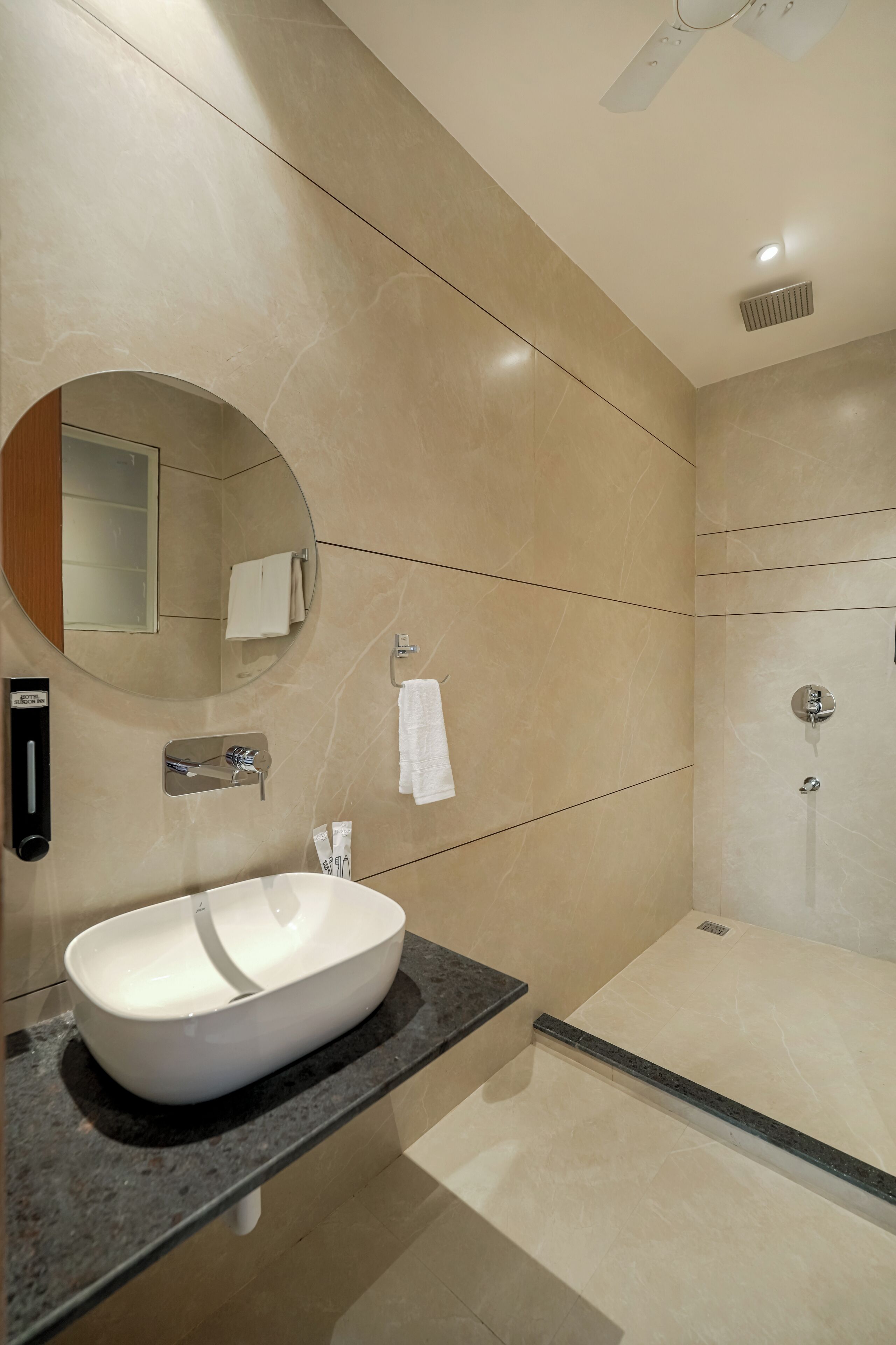 Une salle de bain moderne avec un grand lavabo ovale, un miroir, un porte-serviettes et un espace douche.
