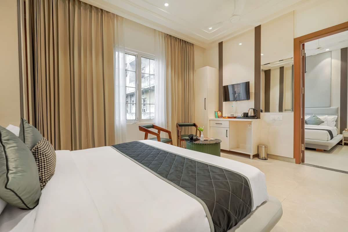 A hotel room with a large bed, a desk with a chair, a TV, and a bathroom visible through an open door.