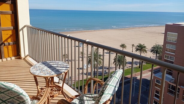 Ein Balkon mit Blick auf den Strand, inklusive Tisch und Stühlen.