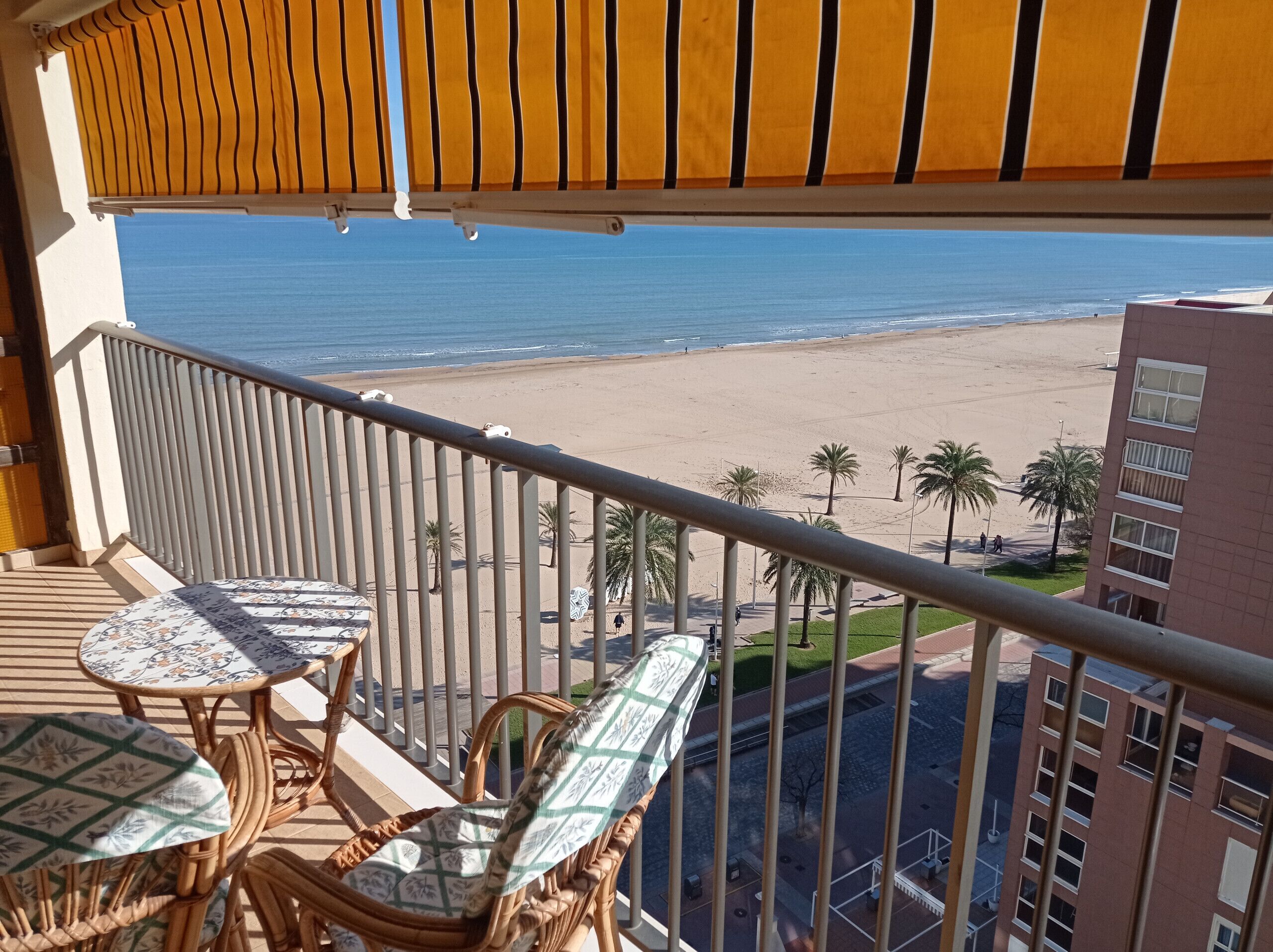 A balcony with wicker furniture and a view of the beach.