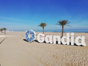 En strand med en skylt som visar ”Gandia” och palmer.