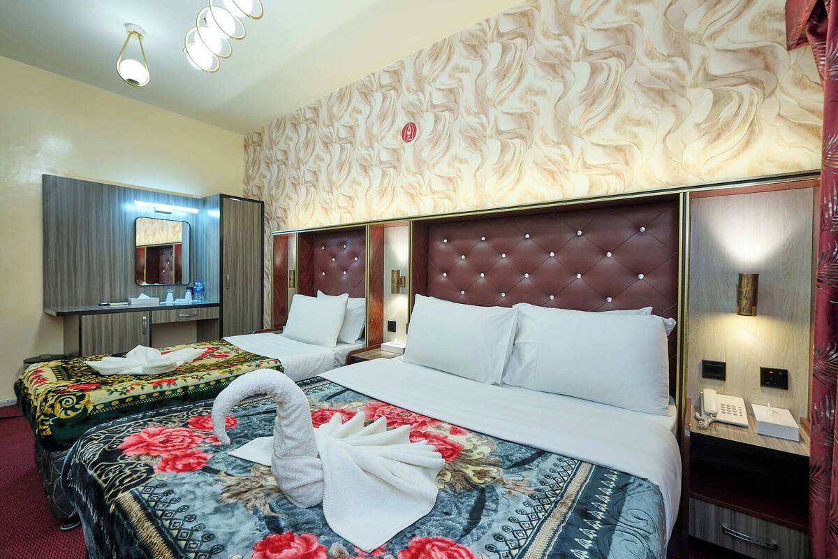 A hotel room with two beds, a large mirror, a vanity, and a telephone.