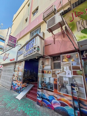 Un hôtel avec une enseigne indiquant « Appartements d’hôtel » et un logo « Qualité ». Plusieurs chambres sont présentées, offrant une vue sur le paysage urbain.
