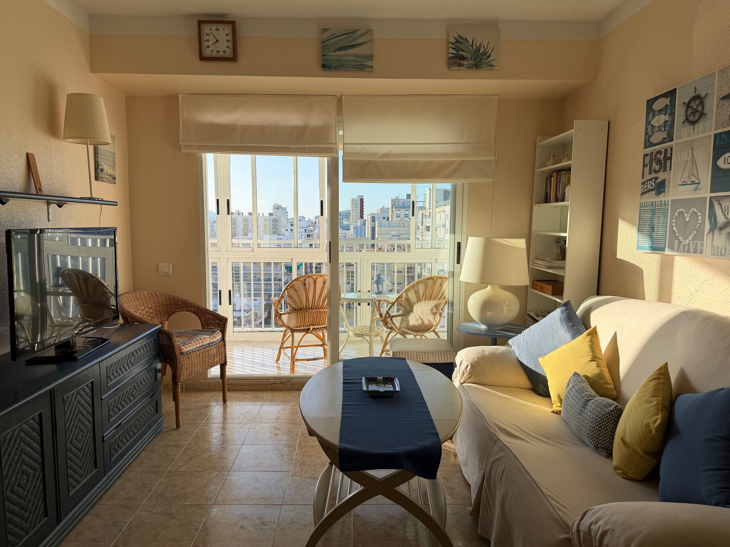 Un salon comprenant un canapé, des fauteuils, une table, un téléviseur et un balcon avec vue sur la ville.