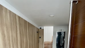 Un pasillo con pared de madera, suelo de baldosas y una puerta que da a una escalera.