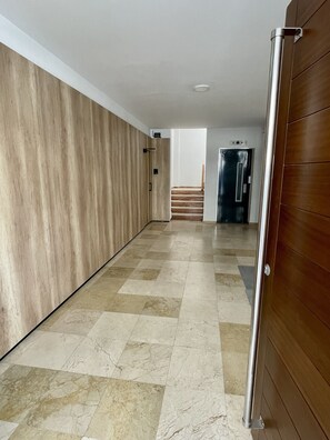 Ein Flur mit Holzwand, gefliestem Boden und einer Tür zu einer Treppe.