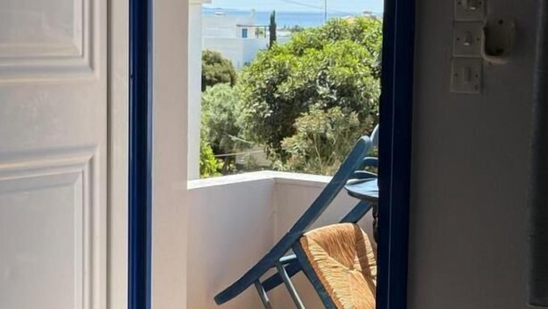 A room with a bed, a window, and a view of greenery outside. - VIAS (Monemvasia)