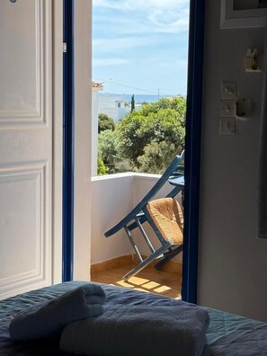 A room with a bed, a window, and a view of greenery outside. - VIAS (Monemvasia)
