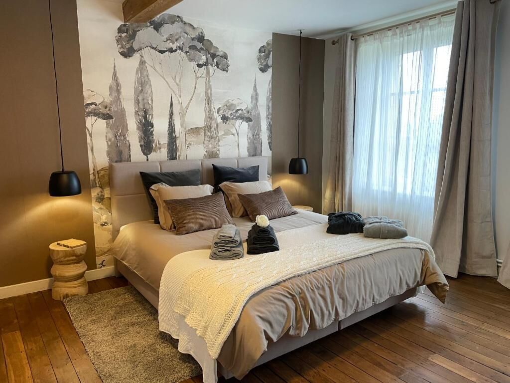 Een slaapkamer met een groot bed, een muurschildering, twee bedlampen en een raam met gordijnen.