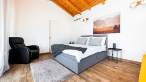 A bedroom with a bed, a chair, a bedside table, a rug, and a painting on the wall. - Villa  Antica Rovinj by Villas Guide (Rovinj)