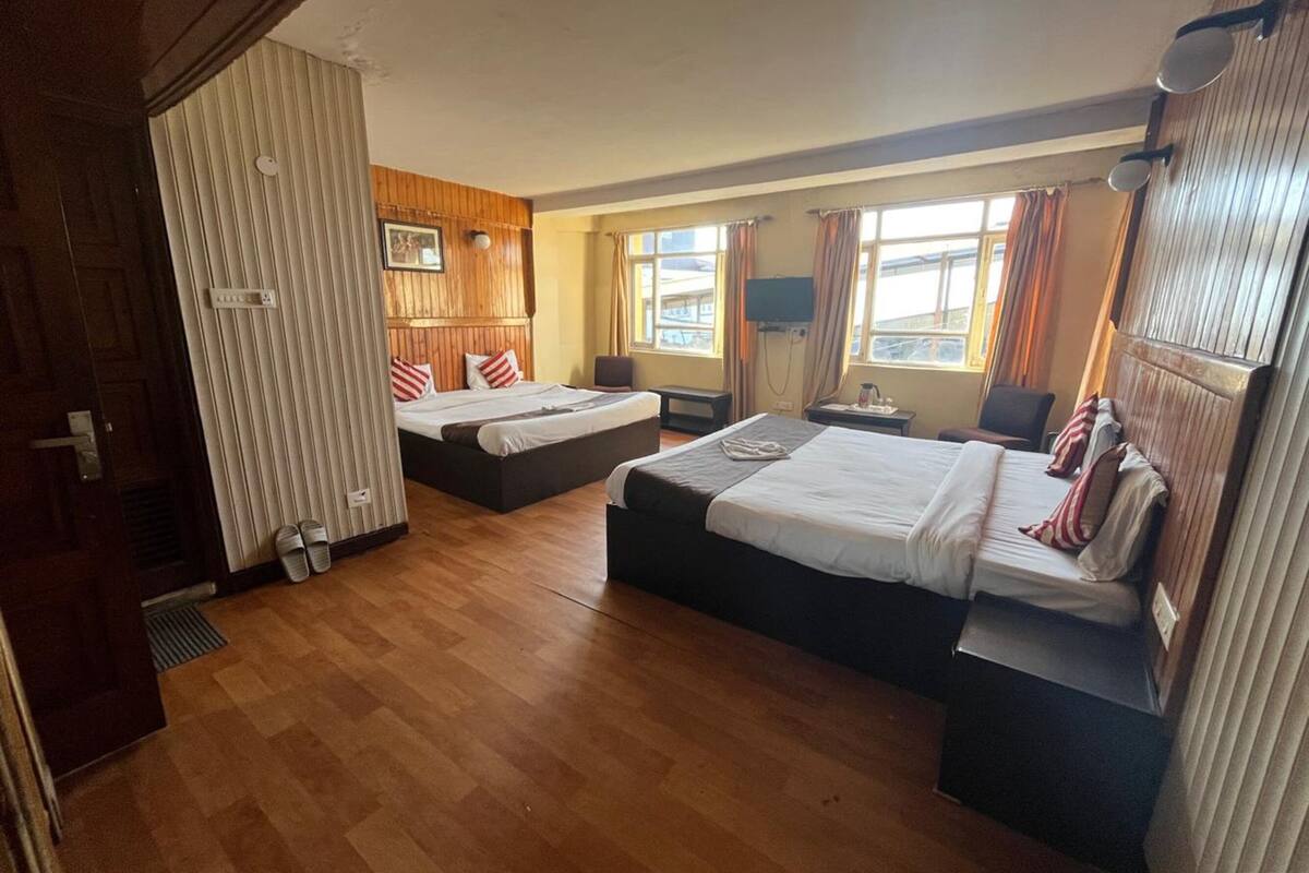 Une chambre d’hôtel avec deux lits, un canapé, une télévision et une fenêtre avec des rideaux.