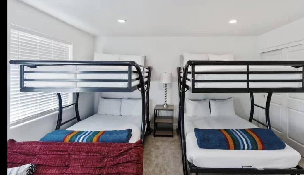 A room with two bunk beds, a small table, and a lamp.