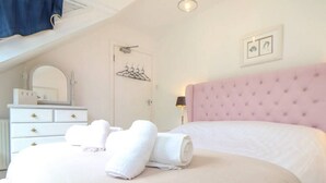 Ein Hotelzimmer mit einem großen Bett, einer weißen Kommode, einem Spiegel und einer Tür mit Kleiderhaken.