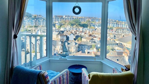 Ein Zimmer mit Erkerfenster und Blick auf eine Stadt.
