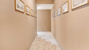 Un couloir dont les murs sont ornés de dessins d’architecture encadrés et dont le sol est recouvert de marbre.