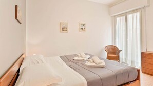 Une chambre à coucher comprenant un lit, une chaise, une commode et deux tableaux encadrés accrochés au mur.
