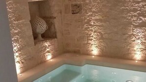 Et spaområde med en stenvæg og et lyseblåt jacuzzi.