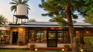 Un edificio de piedra con comedor, depósito de agua y plantas en macetas.