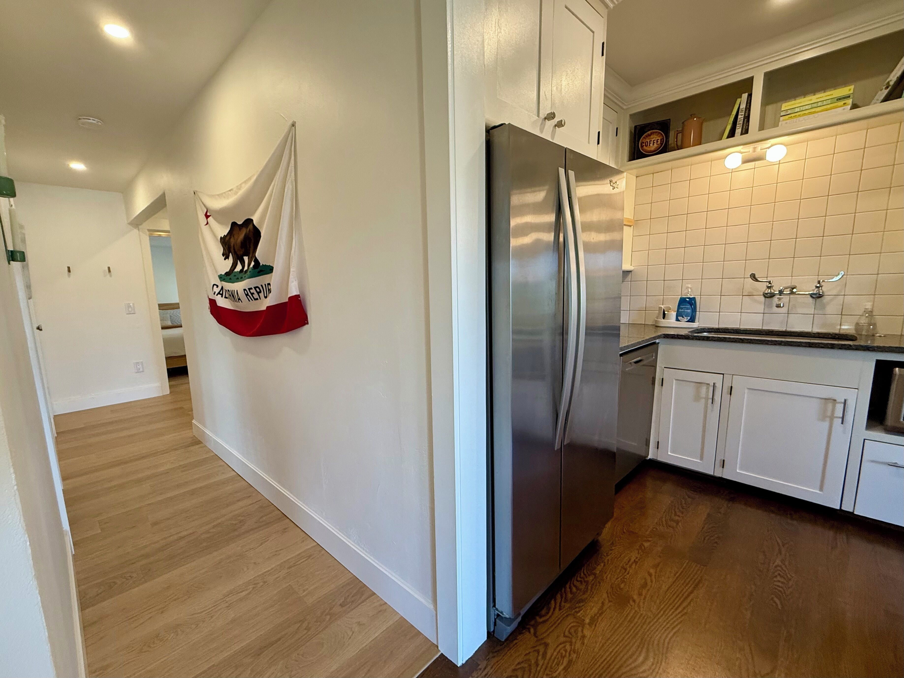 A kitchen with white cabinets, a stainless steel refrigerator, and a tiled backsplash.