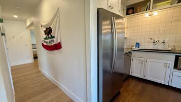 A kitchen with white cabinets, a stainless steel refrigerator, and a tiled backsplash.
