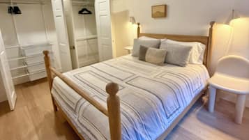 Un dormitorio con una cama de madera, una mesita de noche, una silla, un armario y un ropero.