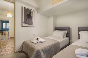 Ein Hotelzimmer mit zwei Betten, einem gerahmten Kunstwerk an der Wand und einer kleinen Sitzecke mit Tisch und Stühlen.