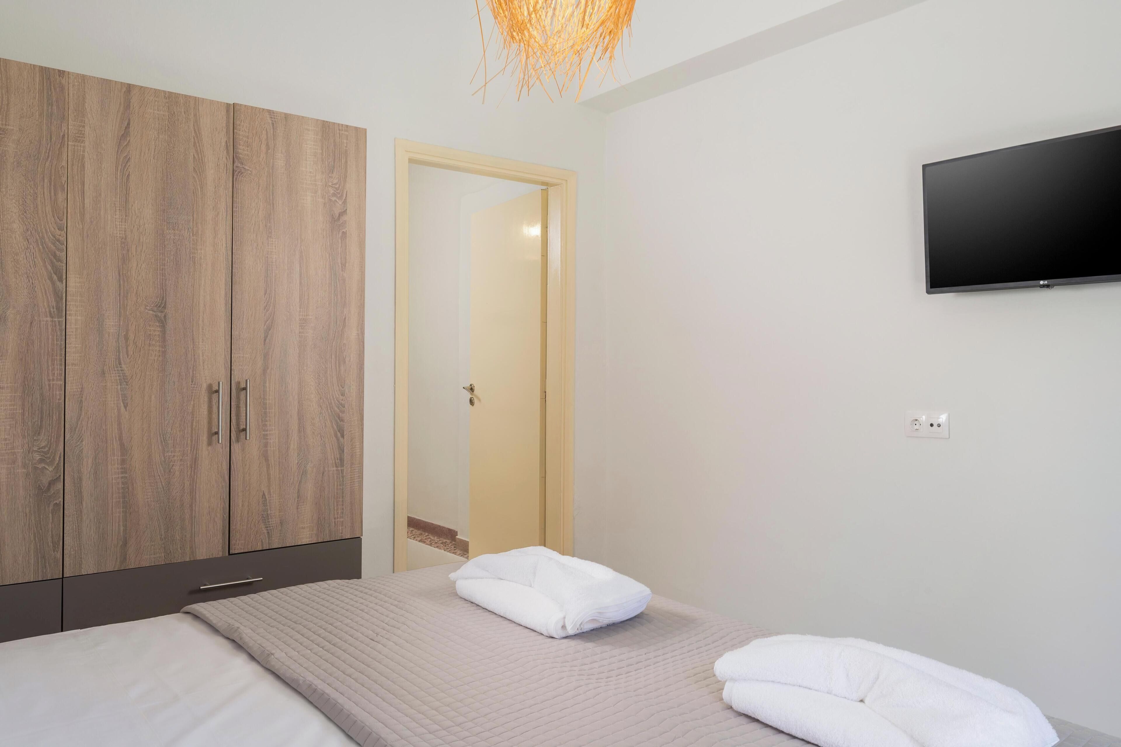 Habitació d'hotel amb un llit, un armari, una televisió i una porta que dona a una altra habitació.