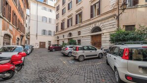 A narrow cobblestone street lined with parked cars and historic buildings with arched windows and balconies. - Nosdom Properties - Piazza Navona Design Apartment (Roma)