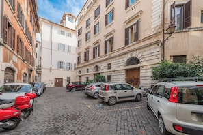 A narrow cobblestone street lined with parked cars and historic buildings with arched windows and balconies. - Nosdom Properties - Piazza Navona Design Apartment (Roma)