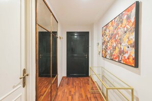 A hallway with a wooden floor, a black door, and a large abstract painting on the wall. - Nosdom Properties - Piazza Navona Design Apartment (Roma)
