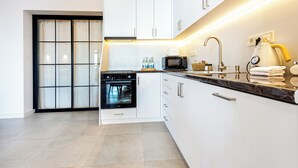 Eine moderne Küche mit weißen Schränken, einem eingebauten Backofen, einer Mikrowelle und einer Kaffeemaschine.
