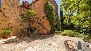 Un patio con un edificio de ladrillo, plantas en macetas y mobiliario exterior.