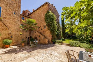 A courtyard with a brick building, potted plants, and outdoor furniture. - Historical Palace with pool (Città della Pieve)
