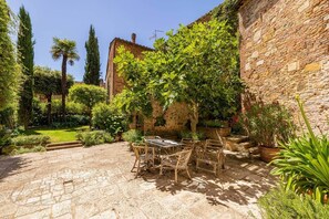 A courtyard with a stone patio, a table with chairs, and various potted plants. - Historical Palace with pool (Città della Pieve)