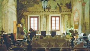 A room with a large table, two windows, and a chandelier.