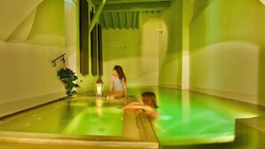 A spa with a green-lit pool, a lantern, and a plant.