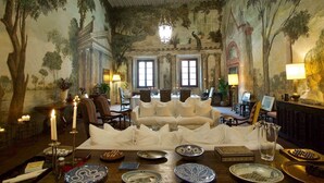 A room with a sofa, chairs, a table with plates, and a chandelier.