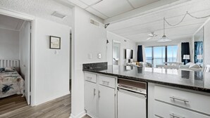 Una cucina moderna con mobili bianchi, un piano di lavoro in granito e vista sull'area living.