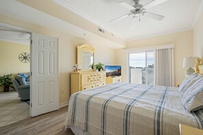 Hotelkamer met een bed, een dressoir, een spiegel, een plafondventilator en een raam met gordijnen.