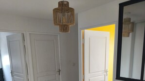 Ein Korridor mit Holzdielen, weißen Türen und einer Pendelleuchte.