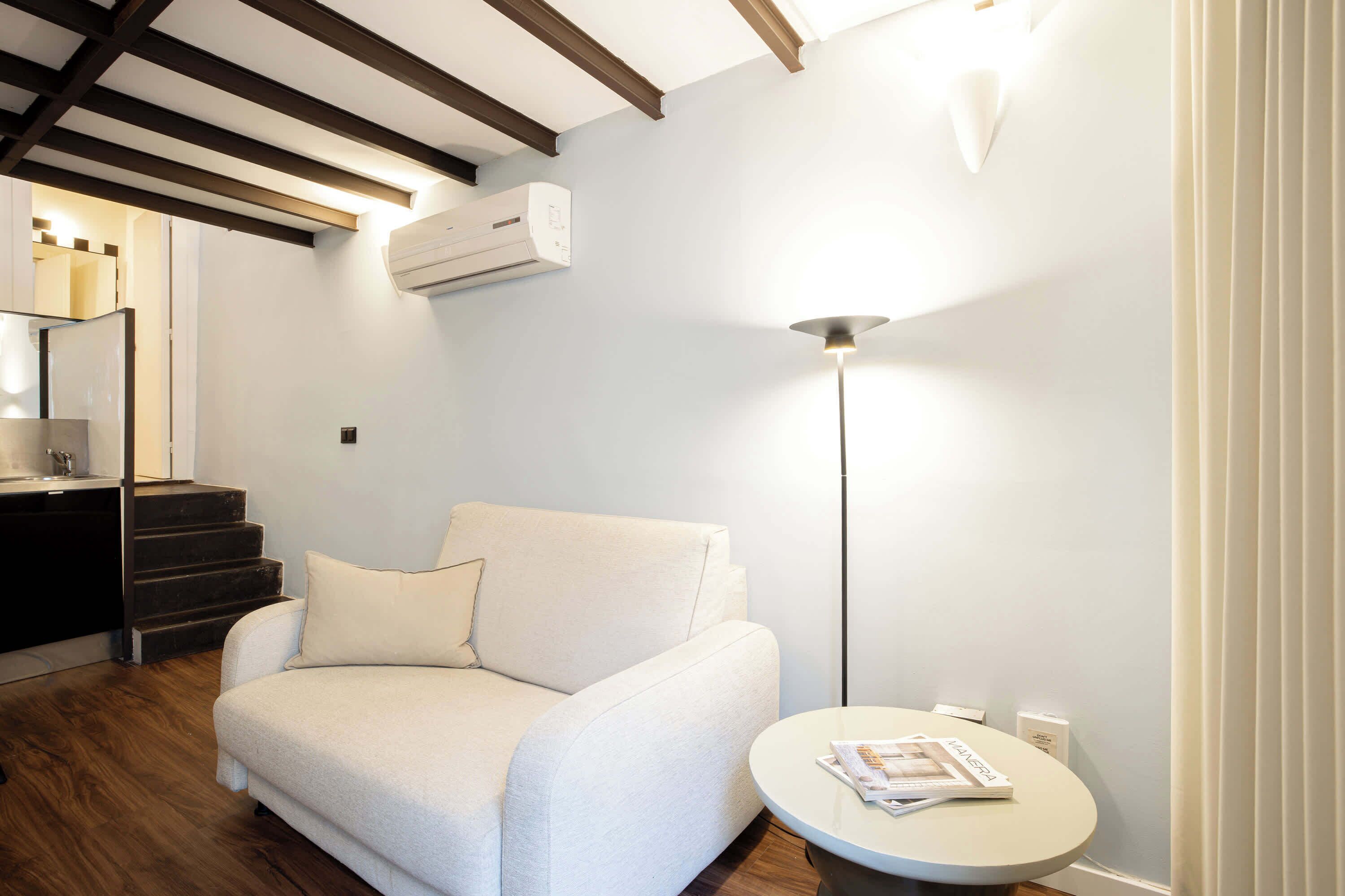 Een moderne woonkamer met een bank, een ronde tafel en een vloerlamp.