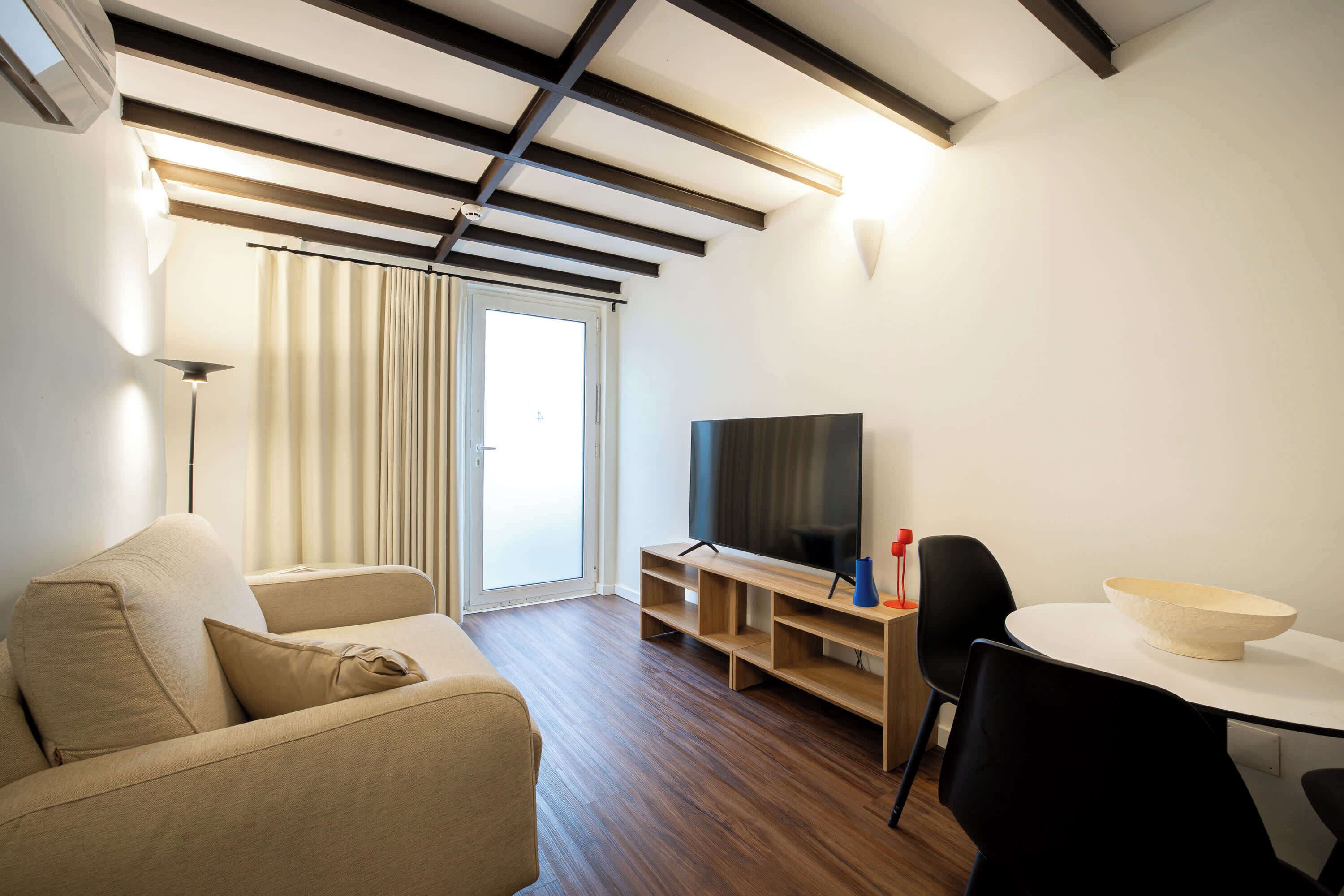 Ein modernes Wohnzimmer mit Sofa, Fernseher und einem Esstisch mit einer Schüssel.