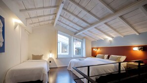 Ein Hotelzimmer mit zwei Betten, einer Holzbalkendecke und einem großen Fenster.