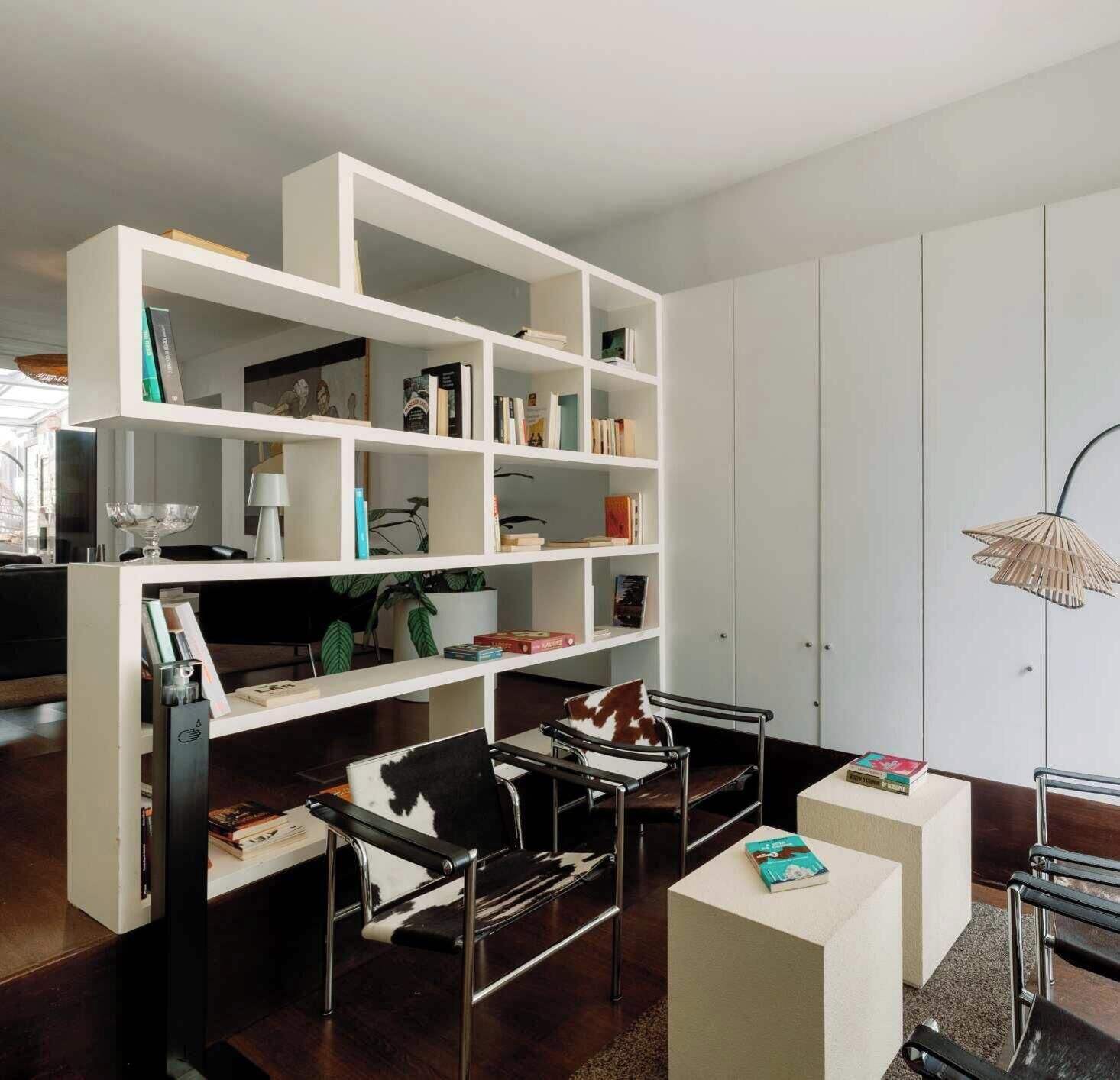 Un salon moderne avec une bibliothèque blanche, un canapé en cuir noir et une table basse.