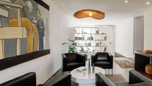 Ein modernes Wohnzimmer mit schwarzen Ledersofas, einem runden Couchtisch und einem großen, abstrakten Gemälde an der Wand.